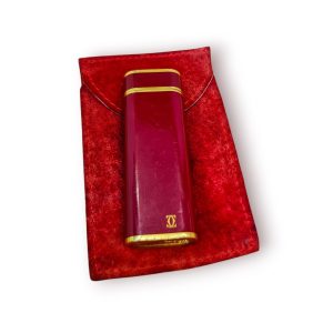 Cartier – Isqueiro “Les Must”, oval, laca Bordeaux & dourado (Swiss Made) – com bolsa