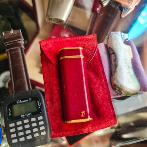 Cartier – Isqueiro “Les Must”, oval, laca Bordeaux & dourado (Swiss Made) – com bolsa